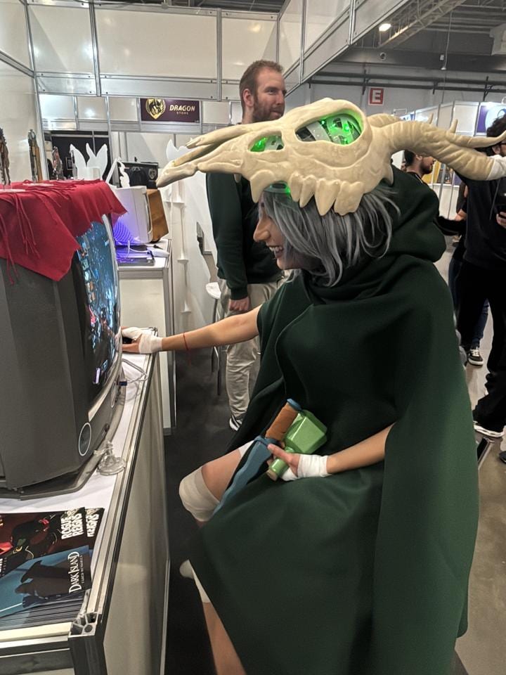 The Slay the Spire cosplayer playing Rogue Reigns on a CRT TV at our booth
